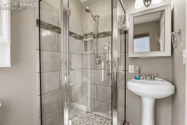 full bath featuring a shower stall and a textured wall