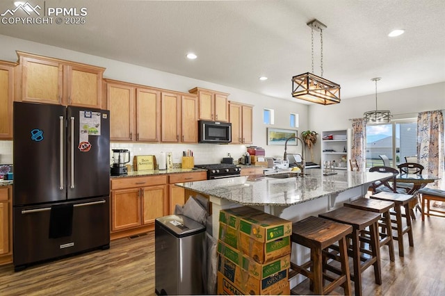 kitchen with decorative backsplash, high end fridge, black microwave, a sink, and gas stove