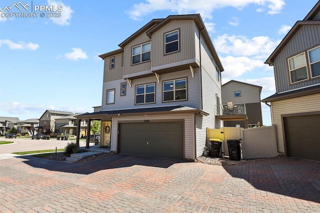 view of front of house with an attached garage, a residential view, fence, and decorative driveway