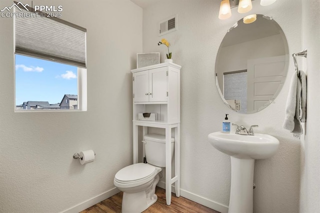 bathroom featuring baseboards, visible vents, toilet, and wood finished floors