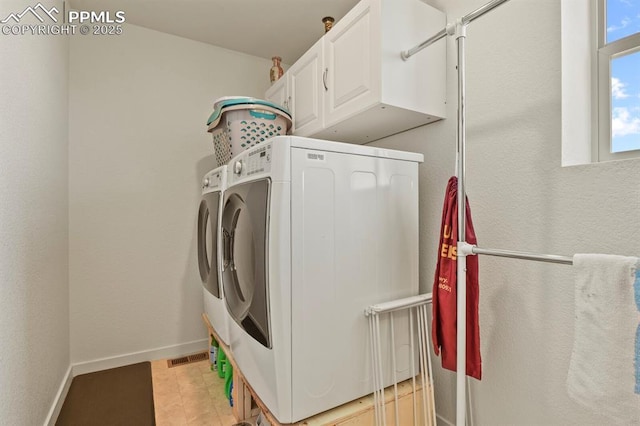 clothes washing area with baseboards, cabinet space, and washing machine and clothes dryer