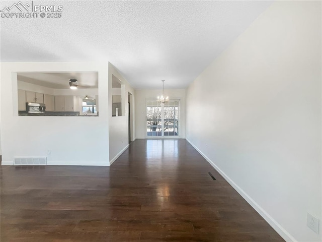 interior space featuring dark wood-style flooring, visible vents, an inviting chandelier, a textured ceiling, and baseboards