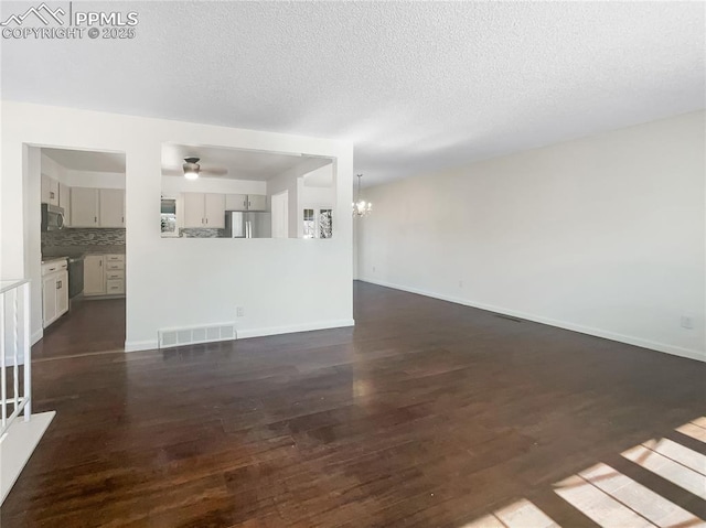 unfurnished living room with dark wood-style floors, baseboards, and visible vents