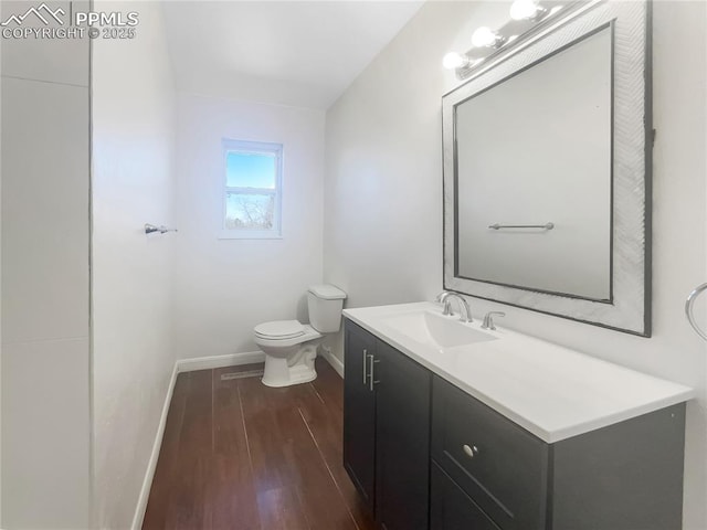 bathroom with toilet, baseboards, wood finished floors, and vanity