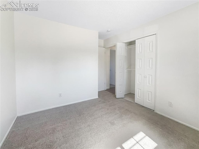 unfurnished bedroom with a closet, carpet flooring, a textured ceiling, and baseboards