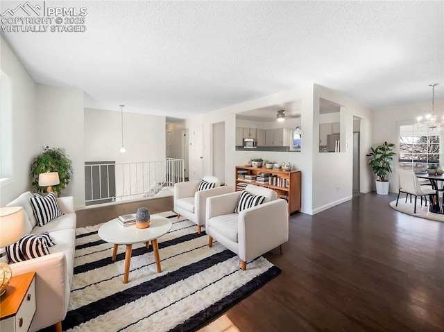 living room with a textured ceiling, baseboards, wood finished floors, and a notable chandelier