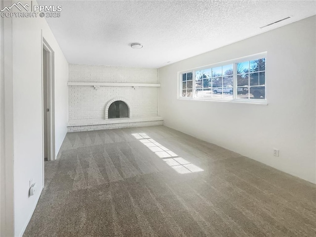 unfurnished living room featuring visible vents, a fireplace, a textured ceiling, and carpet flooring