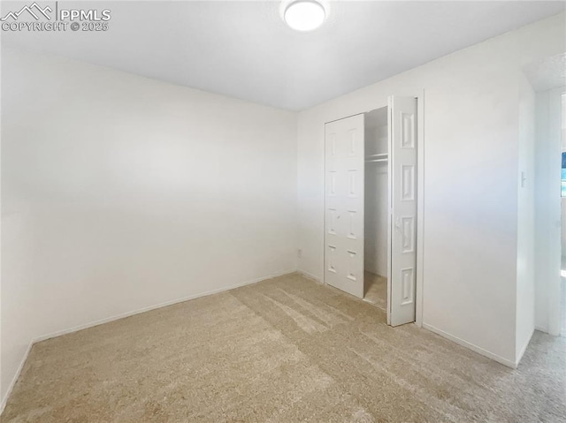 unfurnished bedroom featuring baseboards, a closet, and light colored carpet