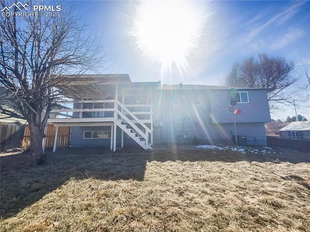 rear view of property featuring fence and stairway