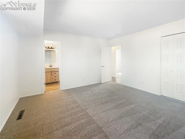 unfurnished bedroom with a closet, carpet flooring, visible vents, and connected bathroom