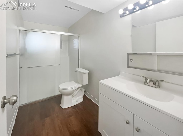 full bath with visible vents, toilet, wood finished floors, a shower with shower door, and vanity