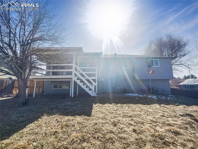 rear view of property with fence and stairway