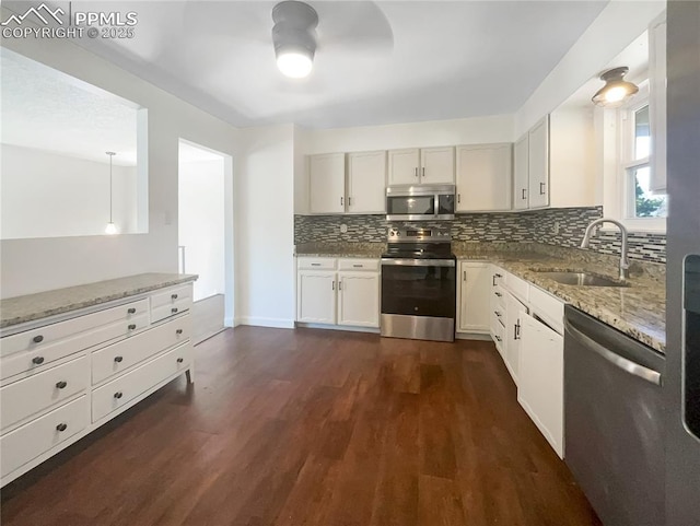 kitchen with light stone counters, dark wood-style flooring, stainless steel appliances, backsplash, and a sink