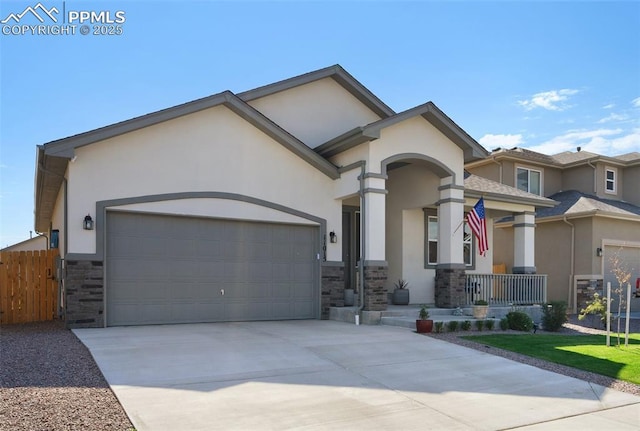 view of front of house with stucco siding, stone siding, fence, concrete driveway, and a garage