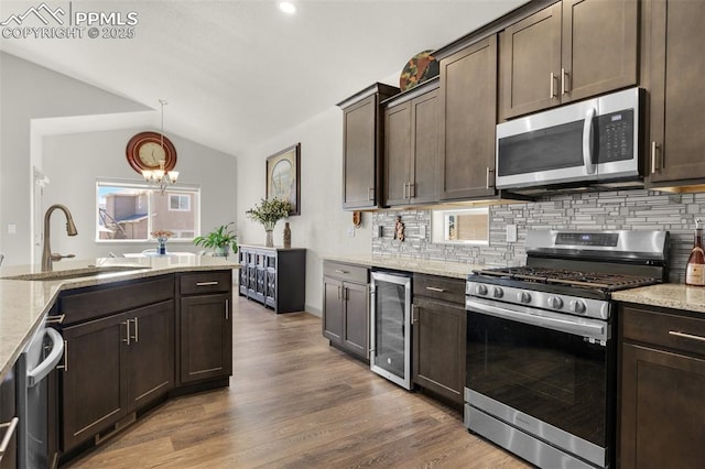 kitchen with a sink, wine cooler, dark brown cabinetry, and appliances with stainless steel finishes