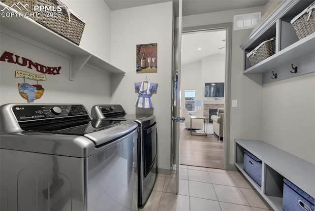 laundry room featuring visible vents, light tile patterned floors, laundry area, a fireplace, and independent washer and dryer