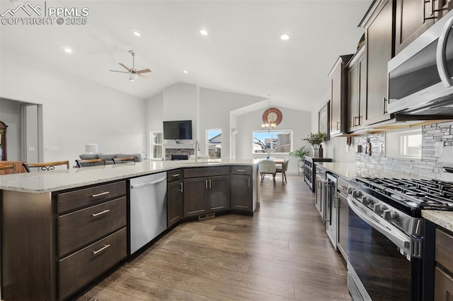 kitchen with dark wood finished floors, dark brown cabinets, stainless steel appliances, and vaulted ceiling