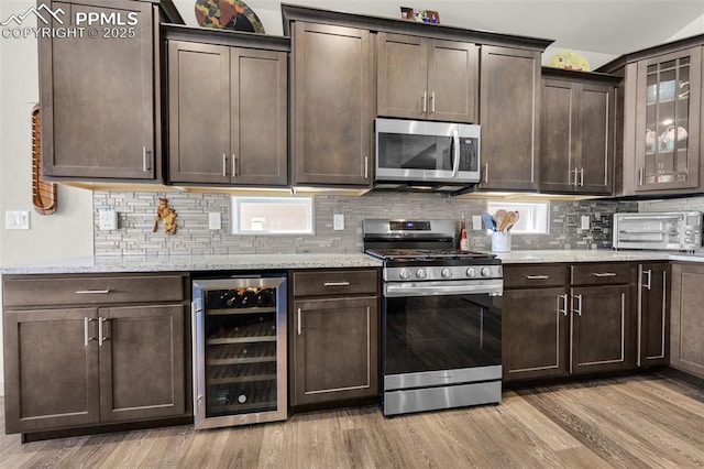 kitchen featuring light wood-type flooring, stainless steel appliances, wine cooler, a toaster, and dark brown cabinets