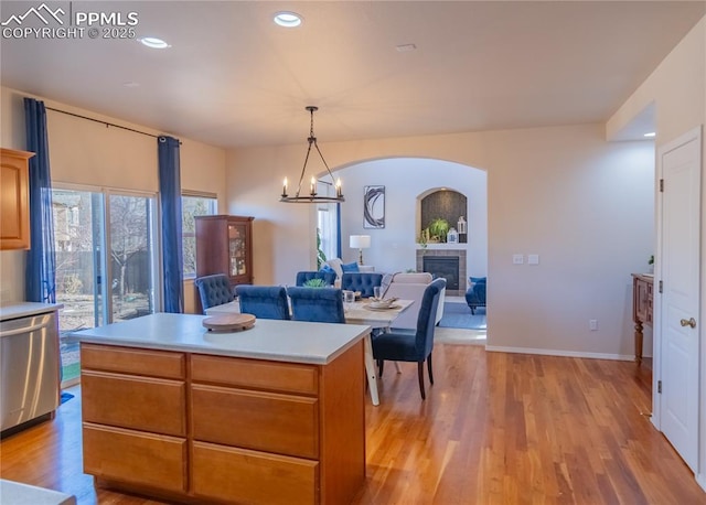 kitchen featuring a tile fireplace, light countertops, light wood-type flooring, stainless steel dishwasher, and recessed lighting