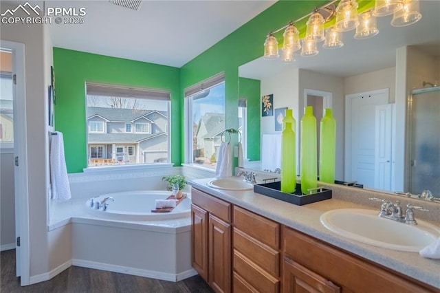 full bathroom with a bath, double vanity, a sink, and a shower with shower door