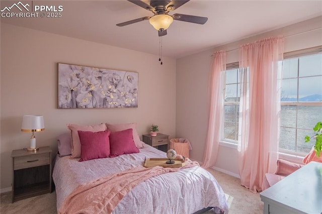 carpeted bedroom with a ceiling fan, multiple windows, and baseboards