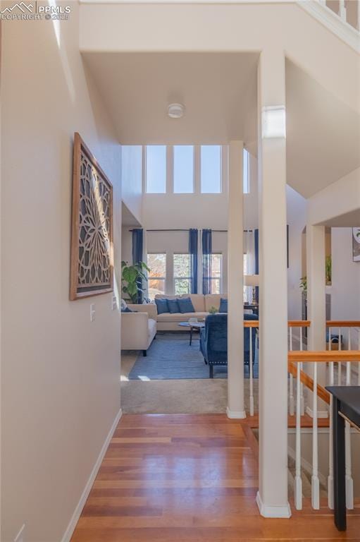 corridor featuring a high ceiling, wood finished floors, and baseboards