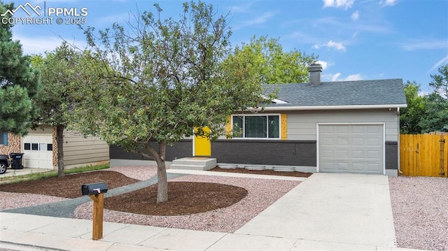 view of front of home featuring brick siding, roof with shingles, concrete driveway, fence, and a garage