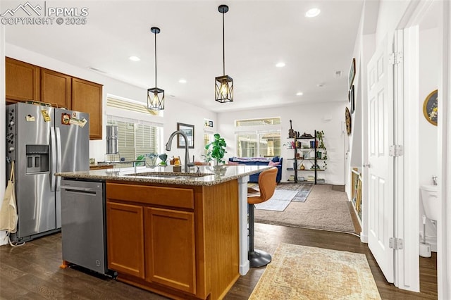 kitchen featuring brown cabinets, dark wood-style floors, stainless steel appliances, and a sink