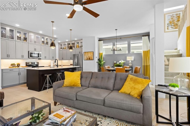 living room featuring recessed lighting, stairs, and ceiling fan with notable chandelier