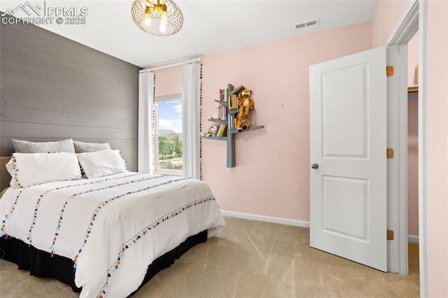 carpeted bedroom with wood walls, visible vents, and baseboards