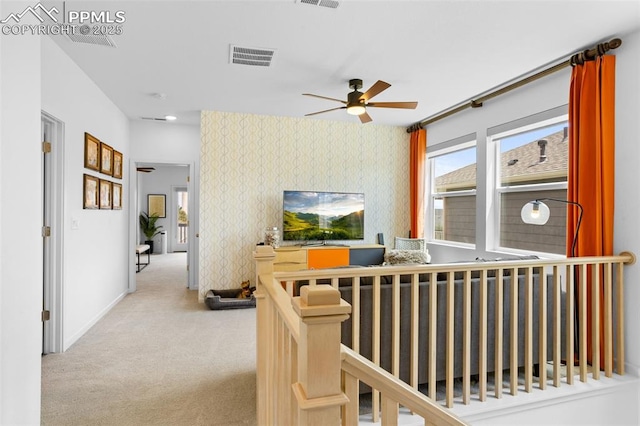 hallway with carpet floors, visible vents, baseboards, an upstairs landing, and wallpapered walls