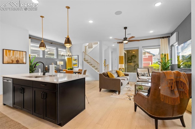 kitchen with a sink, open floor plan, light countertops, dishwasher, and light wood finished floors