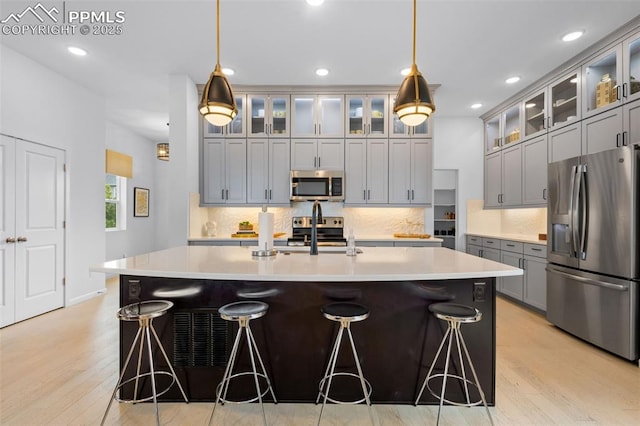 kitchen featuring stainless steel appliances, tasteful backsplash, a sink, and a kitchen breakfast bar