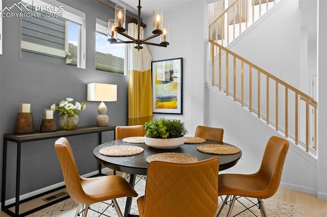 dining room with visible vents, wood finished floors, a chandelier, baseboards, and stairs