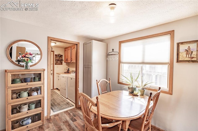 dining area with washing machine and dryer, a textured ceiling, and wood finished floors