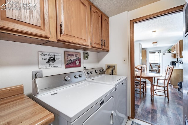 clothes washing area with washer and dryer, cabinet space, a textured ceiling, and wood finished floors