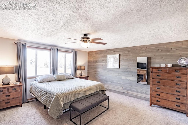 bedroom with wooden walls, light colored carpet, and a textured ceiling