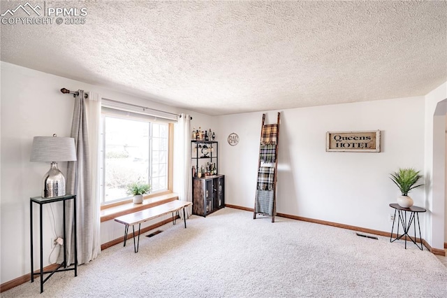 living area featuring visible vents, arched walkways, baseboards, and carpet floors