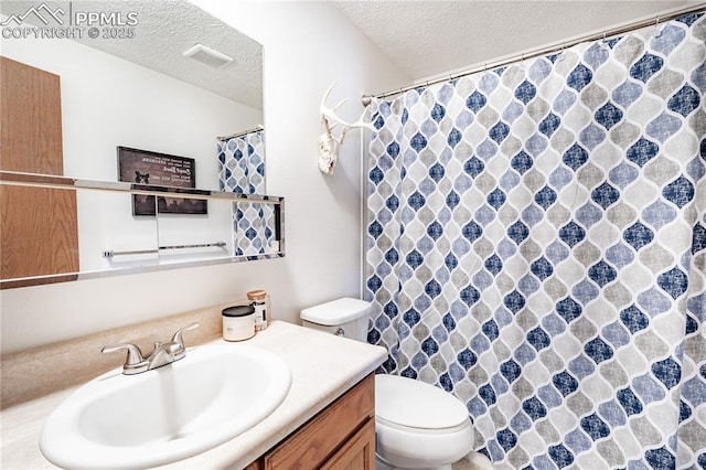 bathroom featuring visible vents, a shower with curtain, toilet, a textured ceiling, and vanity