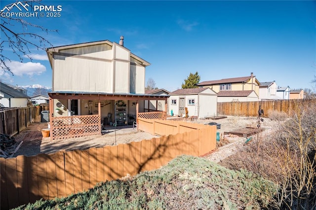 rear view of property with an outbuilding, a fenced backyard, a shed, and a patio area