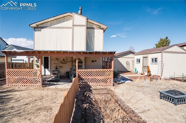 back of house with an outbuilding, a storage unit, and fence