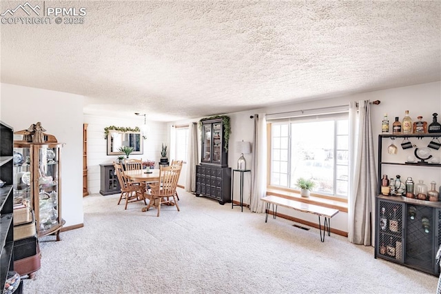 carpeted dining room with a textured ceiling and baseboards