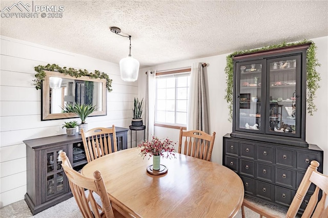 dining area with a textured ceiling and wood walls