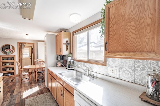 kitchen with a sink, backsplash, wood finished floors, light countertops, and dishwasher