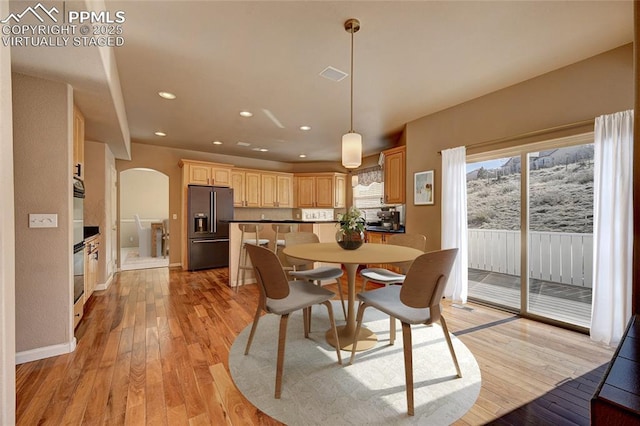 dining space featuring arched walkways, visible vents, light wood finished floors, and recessed lighting