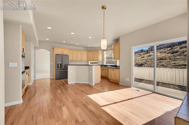 kitchen featuring dark countertops, light brown cabinets, high end refrigerator, and light wood-style flooring