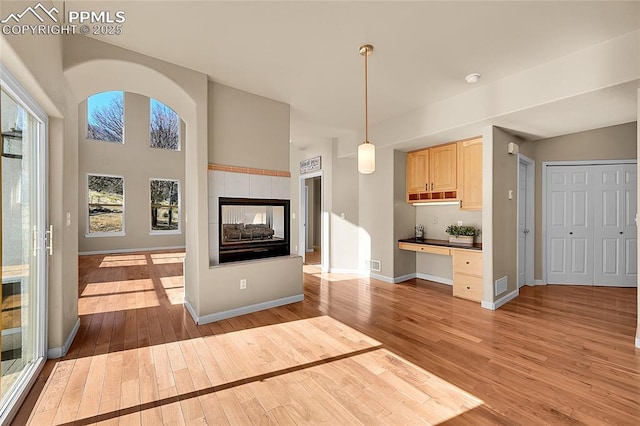 interior space featuring visible vents, baseboards, built in study area, wood-type flooring, and a multi sided fireplace