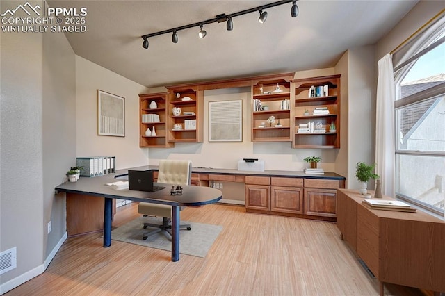 office with light wood-style flooring, baseboards, and built in desk