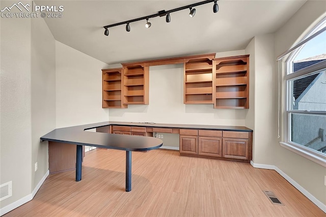 unfurnished office featuring baseboards, visible vents, built in desk, and light wood finished floors