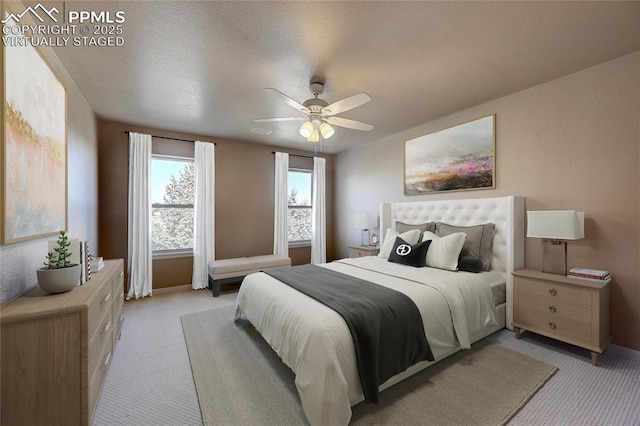 bedroom with ceiling fan, a textured ceiling, and light colored carpet